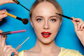 Beauty portrait of a smiling beautiful half naked woman posing with make-up brushes