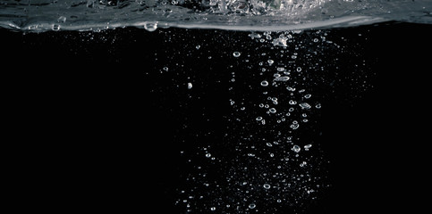 Soda water bubbles splashing and floating drop in black background represent sparkling and...