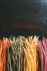 elevated view of arranged colorful tagliatelle pasta placed in row on metal table