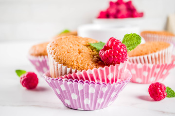Sweet summer dessert, homemade baked muffin with raspberry jam, served with tea, fresh raspberries and mint. On a white marble table, copy space