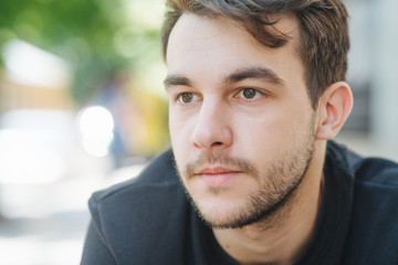 Fototapeta premium An attractive and handsome man with stylish hair and beard, interesting funny story. Portrait of a worried young man at the workplace. Stress concept.