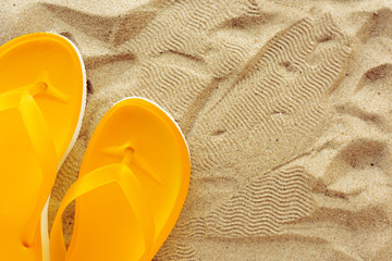 Fototapeta na wymiar Yellow beach flip flops on sand