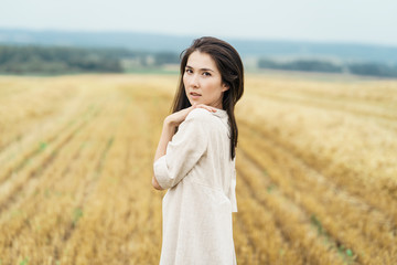 Portrait of Young farmer girl is standing in the middle of row cutted field of hay. Rural lifestyle concept. Space fot text