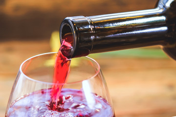 red wine is poured into a glass. wooden background.