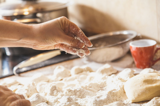 Hands sprinkle with flour raw dumplings on table