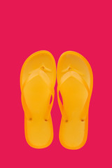 Yellow beach flip flops on neon pink background