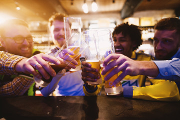 Soccer fans are celebrating their teams victory by saluting with a beer in the local pub.
