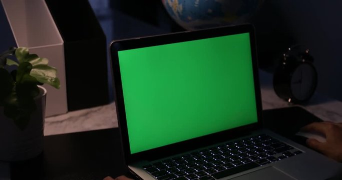 Laptop with green screen. Dark office. Dolly move right to left. Perfect to put your own image or video.Green screen of technology being used. Chroma Key laptop