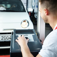 Car mechanic testing light of car in garage