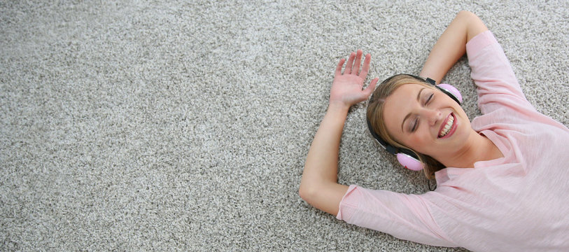 Blond girl relaxing on carpet floor with headphones on, Template