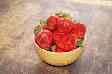 Fresh strawberries in a bowl on a wooden table. Fresh strawberries in a bowl on a wooden table. Vegetarianism, vegan. The concept of health, proper nutrition, diet.