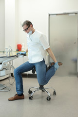 male dentist stretching his legs  in the office during break