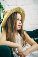 Close up portrait of preschool girl in straw boater hat. Vertical orientation. Summer holidays begins.