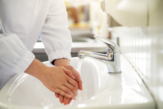 Female worker is sterilizing hands before work.