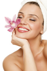 beautiful young woman with a towel on her head hold a orchid on white background