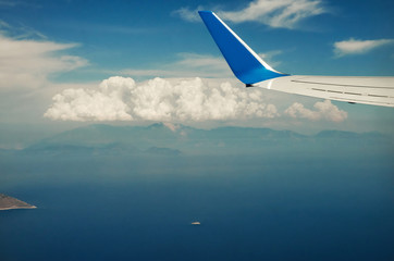 Fototapeta na wymiar View from airplane window travel tourism. Wing of an airplane flying above the clouds over tropical island Turkey