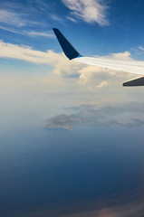 View from airplane window travel tourism. Wing of an airplane flying above the clouds over tropical island Turkey