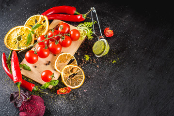 Fresh cherry tomatoes and spices on black background. Top view. Copy space