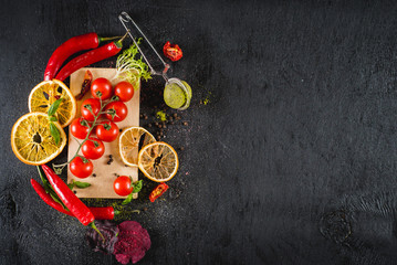 Fresh cherry tomatoes and spices on black background. Top view. Copy space