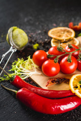Fresh cherry tomatoes and spices on black background. Top view. Copy space