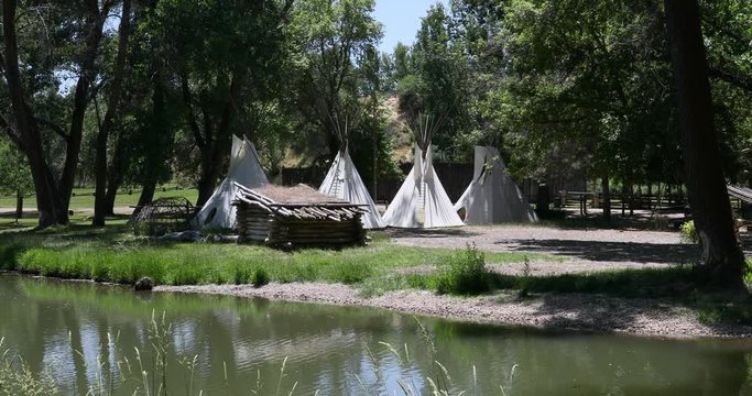 Rendezvous Indian camp along river lake. Fort Buenaventura in Ogden, Utah reproduction of pioneer, trader, hunter and native American Indian teepee camp. Recreation, picnic hiking park.