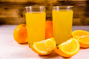 Oranges and glasses with orange juice on a wooden table