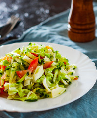 fresh vegetables salad with cabbage, tomato and cucumber in plate on table