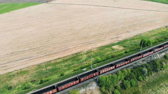 A cargo train moves on a railroad, aerial view. Freight train with cargo containers passing by