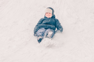 Fototapeta na wymiar A boy is riding a toboggan on a sledge, winter snow is frosty
