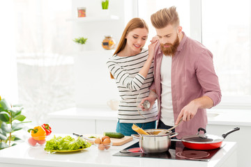Obraz na płótnie Canvas Domestic casual lifestyle idyllic harmony modern concept. Portrait of beautiful couple preparing meal enjoying time together having eggs vegetable salad pasta for dinner