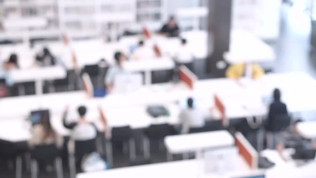 Abstract blurred public library interior with people working and reading on modern desk. Blurry coworking space atmosphere. business and education concepts. 4K video