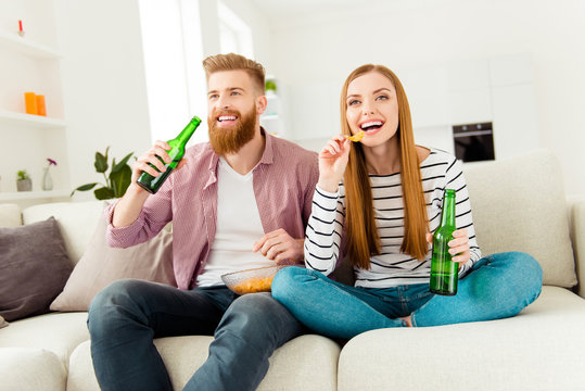 Weekend holiday vacation joy enjoy leisure fun date concept. Excited cheerful joyful delightful attractive rejoicing students eating junk food drinking alcohol beer sitting on divan watching sport