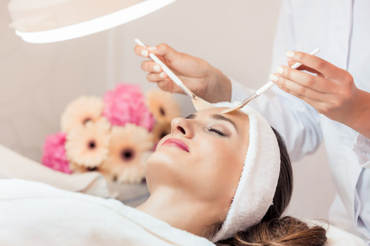 High-angle close-up view of the face of a beautiful woman during anti-aging facial massage with soft brushes in a modern cosmetic center