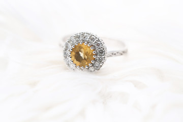 Yellow gem stone and diamond ring on white fabric