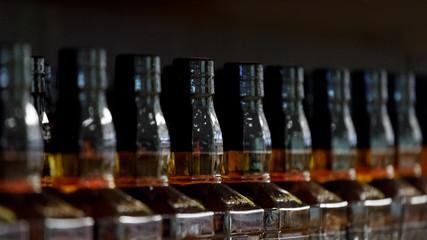 Necks of the bottles of alcohol standing in a row