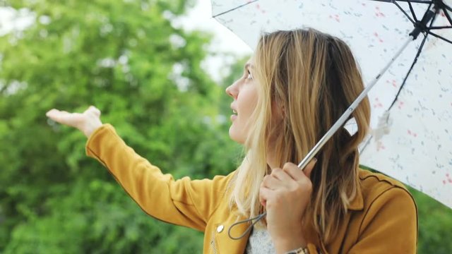handsome pretty woman looking up the sky and raise hand for checking if the rain stop smiling and close her umbrella enjoying the end of the rainy weather peaceful smile glad female face portrait