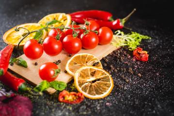 Fresh cherry tomatoes with spices on black background