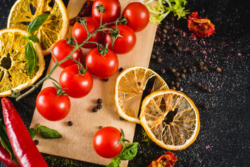 Fresh cherry tomatoes with spices on black background
