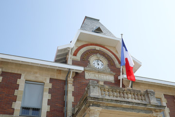 Fototapeta na wymiar city clock attached to the town hall with french flag in cityhall