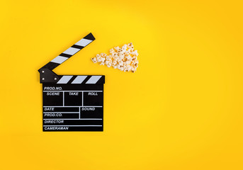 Naklejka premium Cinema background. Popcorn and clapperboard on yellow background