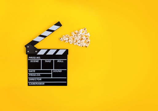 Cinema background. Popcorn and clapperboard on yellow background