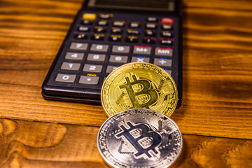 Bitcoins and scientific calculator on a wooden table