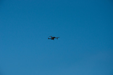 Black quadrupter with propellers flies in the sky and photographs landscapes
