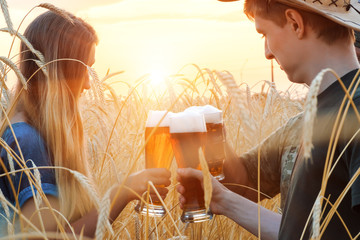 People drink beer in the wheat field during sunset