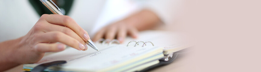 Closeup of woman's hand writing on agenda, template