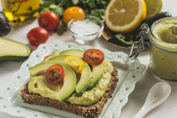 Green Avocado Spread and Organic Slices with Fresh Cherry Tomato as Vegan Breakfast Concept
