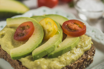 Green Avocado Spread and Organic Slices with Fresh Cherry Tomato as Vegan Breakfast Concept