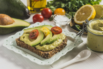 Green Avocado Spread and Organic Slices with Fresh Cherry Tomato as Vegan Breakfast Concept