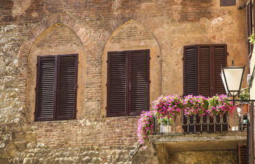 Fototapeta na wymiar Traditional Italian windows with shutters in one of the houses of Siena, Italy