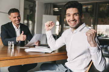 Career, office and placement concept - successful caucasian man 30s rejoicing and clenching fists,...